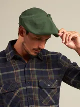 Boina azul marino de paño con visera pequeña y botón decorativo en la parte superior.