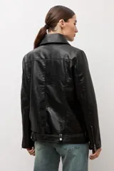 Chaqueta biker de eco cuero color negro, con solapas amplias, cierre cruzado asimétrico, bolsillos laterales con cierre y cinturón ajustable en el dobladillo.