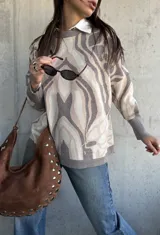 Sweater de punto con diseño abstracto de líneas orgánicas en tonos gris y beige, cuello redondo, manga larga con puños ajustados y corte holgado.