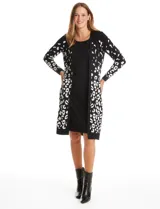Vestido midi de tejido de punto con diseño integrado que simula un conjunto de vestido y cárdigan. Presenta un color base negro con detalles geométricos en blanco en las mangas y el ruedo. Posee escote redondo y mangas largas.