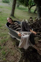 Buzo de tejido de punto grueso en color gris con rayas horizontales en color crema, de corte holgado, cuello redondo y mangas largas.