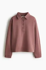 Buzo en tejido liviano color malva con cuello camisero, tapeta de botones, hombros caídos y puños acanalados.