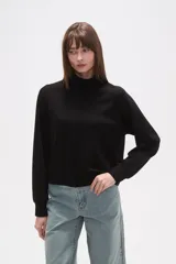 Buzo de manga larga color negro, con cuello alto tipo mock neck y corte holgado. Presenta costuras tipo raglán en los hombros.