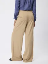 Pantalón de corte recto y pierna ancha, color beige, con cintura de tiro medio y cierre frontal.