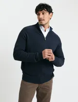 Cardigan de punto color marrón, con cuello alto y cierre frontal completo. Presenta mangas largas tipo ranglan y bolsillos laterales de ribete.
