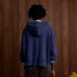 Campera tipo canguro con cierre frontal, color azul marino, de corte holgado y mangas abullonadas con puños ajustados. Presenta un bordado blanco con un monograma estilizado en el pecho.