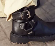 Botas de caña baja color chocolate, realizadas en cuero encerado, con hebillas en la caña y herrajes de níquel. El fondo es de suela negra realizado artesanalmente y el interior está forrado en forrería vacuna.