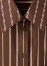 Camisa de algodón con diseño de rayas verticales en tonos marrón y beige, de manga larga, cuello camisero y cierre frontal de botones.