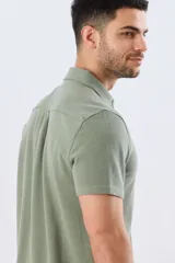 Camisa de piqué lisa color celeste, de manga corta, con cuello camisero y cierre frontal de botones oscuros.