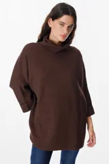 Sweater de tejido de punto suave en color beige, con silueta holgada, cuello alto y mangas tres cuartos con puños definidos.