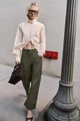 Pantalón de tiro alto en color verde militar, con corte barrel de pernera holgada que se estrecha hacia el tobillo. Presenta trabillas laterales ajustables en la cintura y en el bajo, bolsillos delanteros y cierre frontal con cremallera y botón.