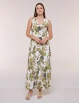 Vestido maxi sin mangas de base blanca con estampado de hojas tropicales en tonos verde y marrón. Presenta escote en V cruzado, cintura elastizada con paneles fruncidos y falda larga fluida con volados en el ruedo.