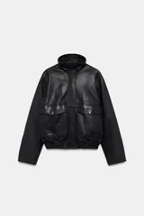 Cazadora de piel 100% color negro de Zara Woman Collection, con cuello subido, manga larga y bolsillos de plastrón con solapa en el delantero. Cuenta con bajo elástico y cierre frontal con cremallera y botones a presión ocultos.
