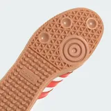 Championes Adidas modelo Samba OG, fabricados en cuero blanco con las icónicas tres tiras y detalles en rojo solar, puntera de nobuk gris claro y suela de goma marrón.