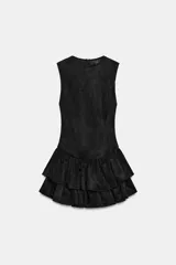 Vestido corto de cuello redondo y manga sisa, confeccionado en tejido efecto ante. Presenta un diseño ajustado en el torso con bajo acabado en doble volante. Cierre posterior con cremallera.