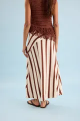 Pollera larga de punto en color beige con rayas verticales marrones, corte evasé y diseño asimétrico en la cintura.
