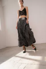 Pollera larga de tejido texturizado con efecto arrugado y acabado satinado, de color gris oscuro, con pretina ancha y silueta acampanada.