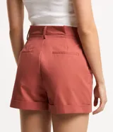 Short de sastrería confeccionado en tricolina de algodón, con diseño de tiro medio, pliegues delanteros, bolsillos laterales y bajo con dobladillo plegado. Cuenta con cierre de botón y cremallera, además de trabillas en la cintura.