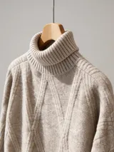 Buzo de punto color beige con cuello alto tipo polera y diseño de tejido con relieve en forma de rombos.