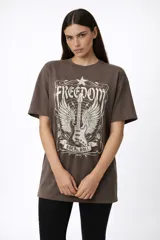Remera de algodón de manga corta y cuello redondo, con diseño holgado y estampado frontal con motivos florales y texto.
