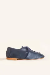 Zapato tipo oxford plano de cuero vacuno en color azul marino, con cordones al tono y suela de cuero.