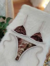 Bikini de dos piezas con corpiño triangular y bombacha de atar, confeccionado en tela de terciopelo elástico con estampado degradé en tonos marrones. El corpiño tiene un broche trasero y breteles regulables, y la bombacha es de corte less brasilero con tiras laterales ajustables.