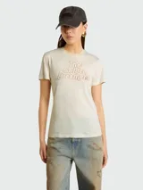 Remera de algodón color crema con cuello redondo y mangas cortas. Presenta una estampa frontal con la frase 'The Golden Dreamers' en letras doradas con contorno marrón.