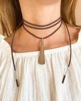 Gargantilla choker marrón de múltiples tiras de gamuza con dije colgante triangular dorado.