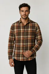 Sobrecamisa de franela a cuadros en tonos marrón, tostado, naranja y blanco, de manga larga con cierre frontal de botones y un bolsillo en el pecho.