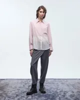 Camisa negra combinada bicolor confeccionada en telas italianas, de silueta holgada. Tiene cuello camisero, cartera con botones, y un bolsillo plaqué. Las mangas largas presentan pliegues en los puños y tablitas en la espalda.