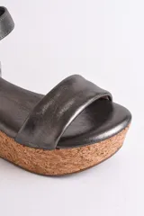 Sandalia plateada con plataforma de corcho, diseño cruzado y tira con hebilla al tobillo.