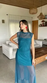 Vestido largo de microtul bordó, sin mangas, con escote alto tipo buche y diseño transparente con forro corto interno que genera un efecto translúcido en la falda.