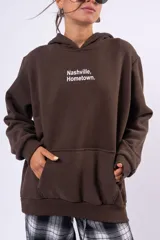 Canguro color marrón chocolate con capucha, bolsillo frontal tipo canguro y estampa pequeña en el pecho con el texto Nashville Hometown.