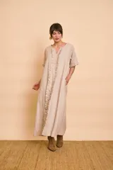 Vestido tipo túnica largo de lino color beige, de manga corta, con detalles de volados en el frente y bolsillos laterales.