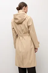 Trench clásico color beige, con cuello alto, capucha desmontable, cierre frontal de botones marrones, bolsillos ribeteados y cinturón ajustable con hebilla.