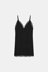 Vestido mini negro con escote en pico y tirantes finos ajustables. Presenta detalles de encaje combinado a tono en el escote y en el ruedo.