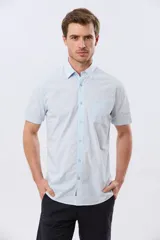 Camisa lisa de manga corta y corte slim, color celeste, con cuello camisero, cierre frontal de botones y un bolsillo aplicado en el pecho.
