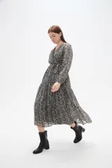 Vestido midi de corte evasé con estampado animal print en tonos oscuros. Presenta escote en V cruzado, mangas largas con puños y falda con volados escalonados.
