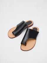 Sandalias chatas de cuero color off-white, con diseño minimalista de tira ancha asimétrica y presilla para el dedo.