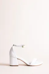 Sandalia de taco cuadrado color blanco, confeccionada en 100% cuero, con tira delantera en el empeine, talón cerrado y pulsera tobillera ajustable con hebilla metálica dorada.