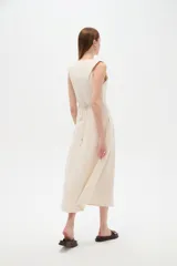 Vestido midi color beige claro, con cuello en V, sin mangas y corte entallado con pinzas.
