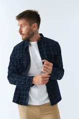 Camisa de pana a cuadros en tonos azul y bordó, de corte regular, manga larga, con cartera de botones y bolsillo frontal.