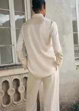 Camisa de poliéster con acabado satinado y diseño liso, cuello camisero, cierre frontal con botones y manga larga.