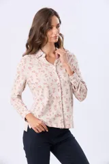 Camisa de jersey de algodón color beige con estampado floral en tonos rosados y marrones, cuello camisero, manga larga con puños abotonados y cierre frontal con botones.
