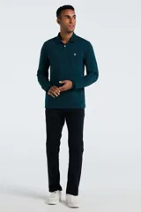 Polo de manga larga color verde oscuro (teal) con cuello polo y tapeta de dos botones. Presenta un pequeño logo bordado de pingüino en el pecho.