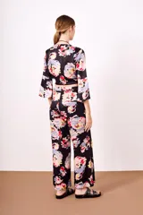 Pantalón negro con estampado floral multicolor, de corte acampanado y cintura elástica con cordón ajustable.