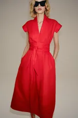 Vestido midi rojo de la colección ZW de Zara, confeccionado en hilatura con lino. Cuenta con escote en pico, manga corta, bolsillos laterales ocultos en la costura, falda de corte evasé y cierre frontal con cinturón ajustable del mismo tejido.