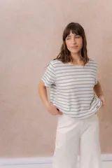 Remera de calce relajado con diseño de rayas horizontales celestes sobre fondo beige, escote redondo y manga corta.