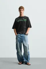 Camiseta boxy fit de punto tejido en hilatura de algodón, color negro con efecto lavado. Cuello redondo y manga corta. Estampado frontal con letras en blanco y verde.