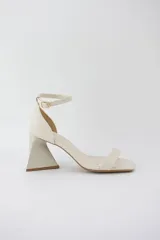 Sandalias color crema con tira delgada sobre los dedos, pulsera al tobillo con hebilla y taco geométrico.